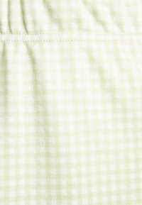Tecido em padrão de quadrados gingham em verde claro e branco, com uma textura suave, apresentando um padrão de grelha e costuras alinhadas.