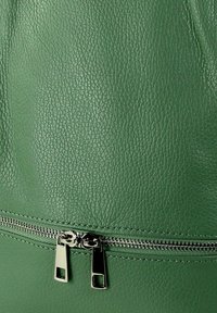 Groene leren tas met een gestructureerde afwerking, voorzien van een zilveren rits met twee trekstangen en contrasterende stiksels langs de naad.