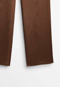 Pantalon marron droit avec une texture lisse, montré de la mi-cuisse jusqu'à l'ourlet sur un fond blanc uni.