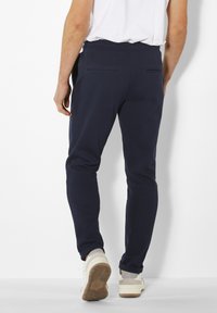 Marine joggers gemaakt van zachte stof, met een slim fit, elastische tailleband, achterzakken en taps toelopend ontwerp. Casual schoenen zichtbaar.