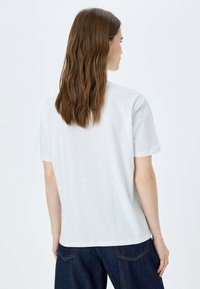 Hvid bomulds t-shirt med korte ærmer, rund halsudskæring og en afslappet pasform. Glat tekstur, uden mønstre eller synlige hardwaredetaljer.