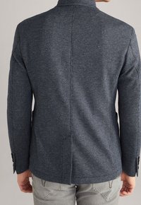 Textured dark blue blazer with a tailored fit, featuring subtle herringbone pattern, single-breasted design, and buttoned cuffs.