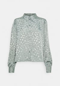 Lys grøn bluse i satin med leopardlignende hvide pletter. Har krave, knaplukning og lange pufærmer.