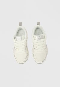 Adidași albi cu partea superioară din plasă și material sintetic, șireturi și un accent argintiu reflectorizant; au o buclă la călcâi pentru o încălțare ușoară.