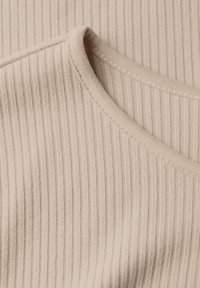 Beige ribbattuotte kihnityäpinne; sisältää pyöreän kaula-aukon ja siistit saumat reunoilla.