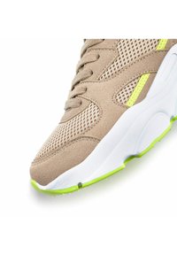 Beez sneaker koos kohevast ülemisest osast, neoonkollaste aktsentidega ja valge tallaga. Omab ümarat ninaosa ja tekstuurseid materjale haardumise tagamiseks.