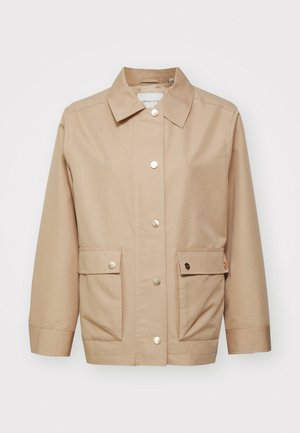 Beige jacket made of cotton canvas, featuring a collar, front buttons, and two front pockets with snap flaps. Smooth texture, casual design.