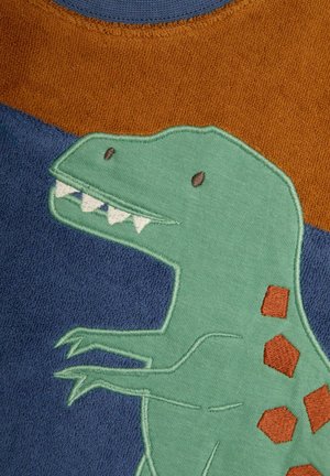 Roheline dinosauruse tikand kangal, millel on sinised ja pruunid sektsioonid. Dinosaurusel on teravad hambad ja pruunid kuusnurksed aktsendid.