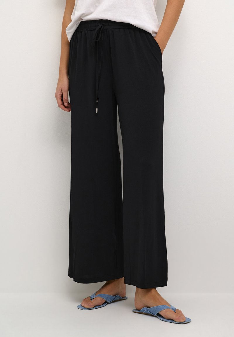 Zwarte wijde broek met een trekkoord in de taille, gemaakt van zachte stof. Heeft zijzakken en een ontspannen pasvorm, geschikt voor casual dragen.