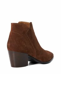 Bottine en daim marron avec un bout pointu, un talon empilé et des détails de couture sur le dessus. Doublure en cuir lisse à l'intérieur.