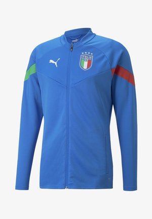 Chaqueta de fútbol italiana azul con cremallera completa, logo de Puma en el pecho derecho, escudo de Italia en la izquierda, rayas verdes y rojas en las mangas.