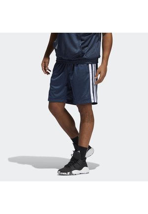 Mann trägt marineblaue Basketball-Shorts aus Mesh mit weißen Seitenstreifen, schwarze Sportsocken und schwarz-weiße Sportschuhe, steht seitlich.