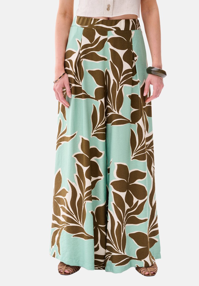 Brede broek van lichtgewicht stof, met een turquoise achtergrond en grote bruine en crèmekleurige bloemenpatronen.