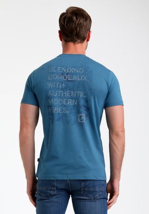 Camiseta azul de hombre hecha de algodón, con texto en un tono más claro en la parte trasera. Mangas cortas y un diseño de corte regular.