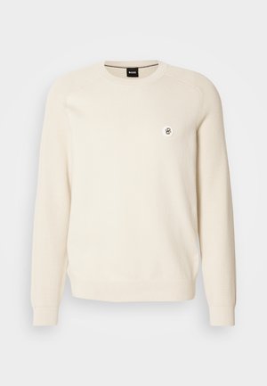 Maglione color crema con texture a coste, scollatura rotonda e maniche lunghe. Presenta un piccolo logo sul lato sinistro del petto. Realizzato in tessuto morbido.