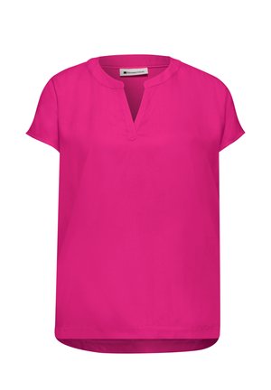 Jasnoróżowa bluzka z krótkim rękawem, okrągłym dekoltem i małym, V-kształtnym wcięciem z przodu na dole, nieco dłuższa z tyłu.