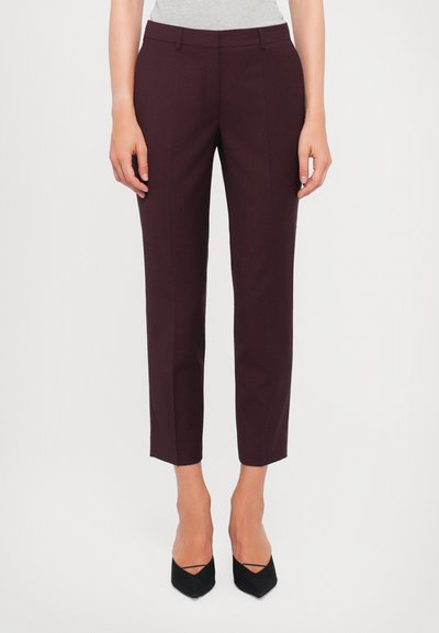 Pantalons bordeaux ajustés slim fit, avec deux poches avant, un devant plat et une longueur cropped, associés à des escarpins noirs à bout pointu.