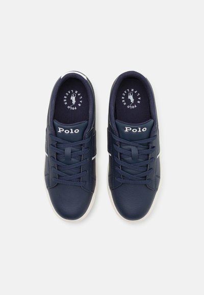 Zapatillas azul marino con parte superior de cuero sintético, detalles en blanco y cordones. Presentan un logo en la lengüeta y una suela texturizada. Acabado suave.