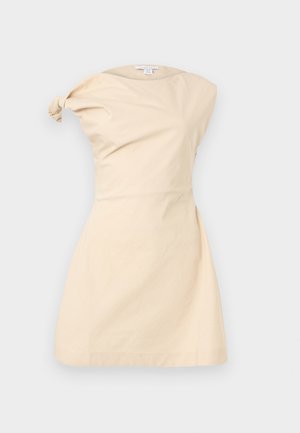 Μπεζ φόρεμα χωρίς μανίκια με ασύμμετρη λεπτομέρεια με στριμμένο κόμπο στον αριστερό ώμο και εφαρμοστή μέση, εμφανιζόμενο σε απλό φόντο.