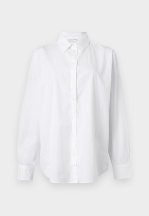 Άσπρο πουκάμισο με μακριά μανίκια, κουμπιά, γιακά και μανσέτες, κατασκευασμένο από λείο ύφασμα, εκτεθειμένο σε απλό ανοιχτό φόντο.