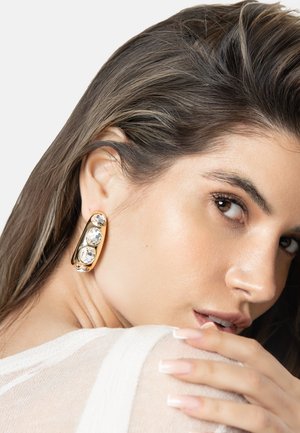 Gold earrings feature three large clear stones in a rounded rectangular design. The surface has a polished finish, enhancing their shiny appearance.