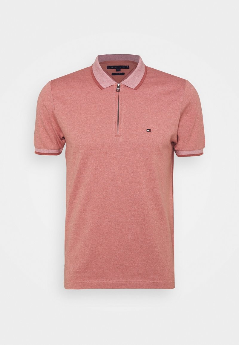 Polo pour homme à manches courtes rose poussiéreux avec fermeture éclair à l’avant, col et poignets côtelés, et petit logo sur le côté gauche de la poitrine.