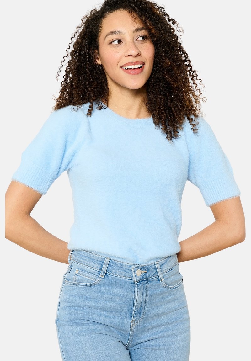 Light blue fluffy short-sleeve sweater with a round neckline, soft texture, and ribbed cuffs. Paired with high-waisted light blue jeans.