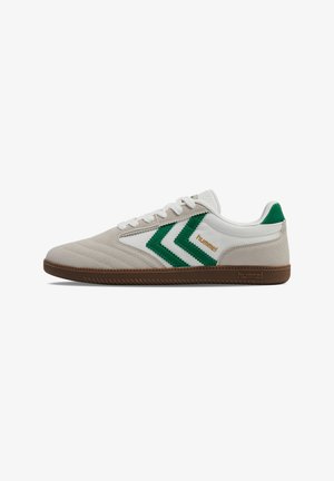 Lage beige en witte sneaker met groene chevronstrepen, witte veters en bruine zool, met het merk "hummel" op de zijkant en hiel.