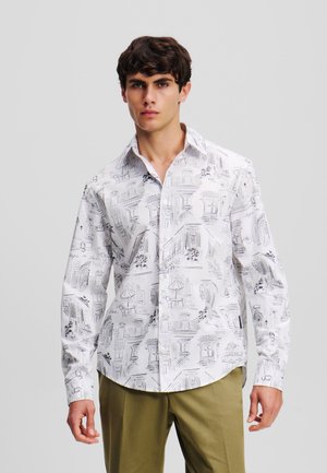 White long-sleeve shirt featuring a detailed monochrome sketch pattern of buildings and floral elements; buttoned front, classic collar.