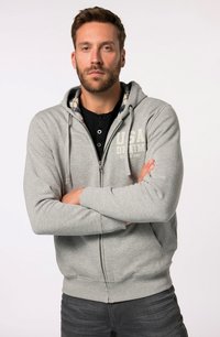 Sudadera gris con cremallera, capucha con cordón, bolsillos frontales y un logo color crema. Camiseta negra debajo, jeans grises y una textura plana.