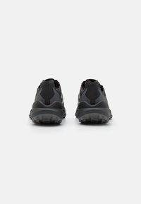 Black athletic shoes featuring a textured sole, mesh and synthetic upper, and cushioned heel, with reflective accents on the back.
