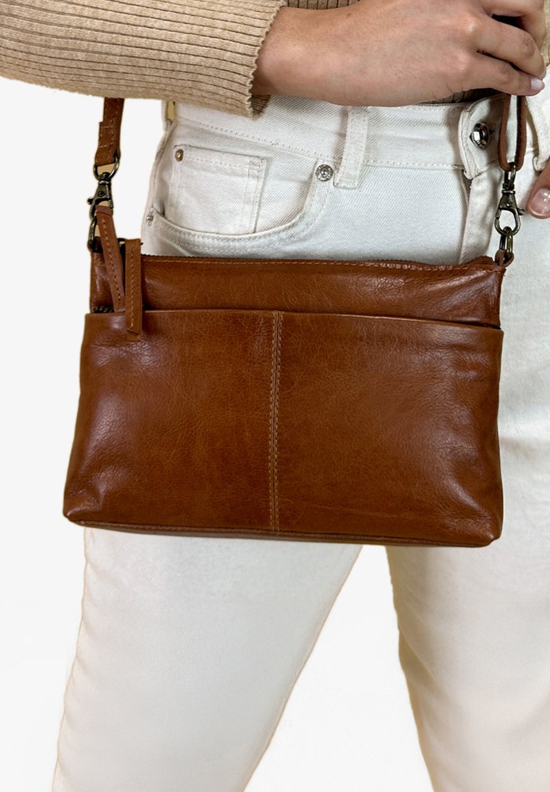 Hnědá kožená crossbody taška s hladkou texturou, obdélníkovým tvarem a přední kapsou, s odnímatelným ramenním popruhem.