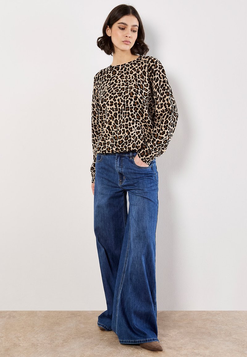 Leopard print long-sleeve top in beige and brown, paired with high-waisted blue wide-leg jeans. Smooth texture with relaxed fit.