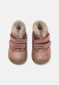 Růžové metalické dětské boty s dvěma suchými zipy, plyšovým beránkem uvnitř a gumovou podrážkou. Zaoblená špička a prošívané detaily.