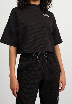 Svart kort sweatshirt med ett strukturerat rutmönster, ribbat krage och korta ärmar. Kombineras med matchande avsmalnande joggers med dragsko.