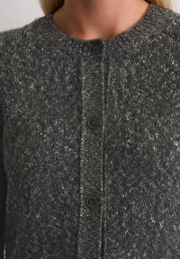 Cardigan lavorato a maglia grigio scuro con scollatura tonda, tessuto testurizzato e cinque bottoni marroni lungo la chiusura frontale.
