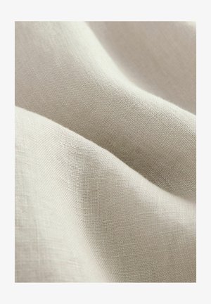 tela de lino beige claro con una superficie texturizada, mostrando caídas suaves y fluidas y un patrón de tejido fino.