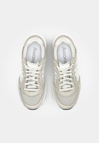 Light beige athletic shoes with mesh and suede materials, flat laces, padded collars, and white accents. Cushioned soles.