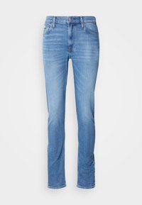 Jeans en denim bleu clair avec une coupe droite, un design à cinq poches et une fermeture à bouton à la taille. Légères marques d'usure sur les cuisses.