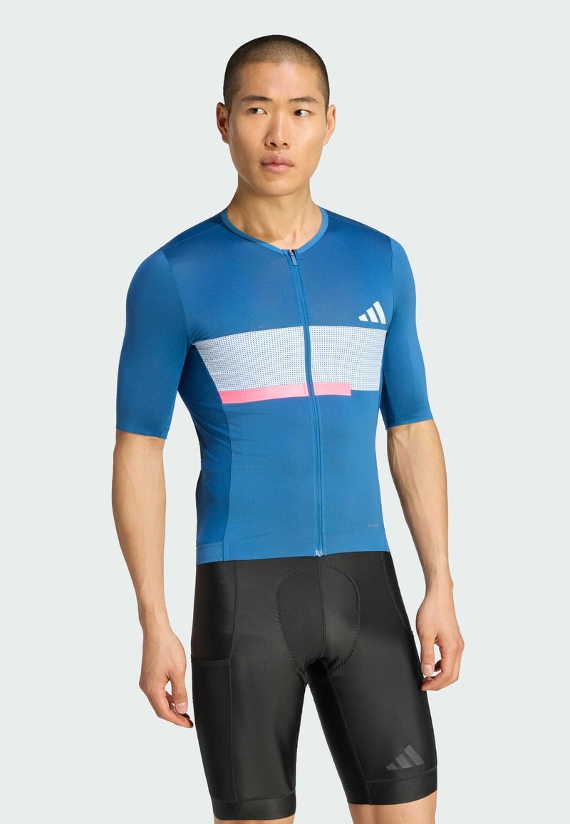 Blaues Radtrikot aus atmungsaktivem Stoff mit kurzen Ärmeln, versehen mit weißen und rosa horizontalen Streifen. Schwarze gepolsterte Radhose.
