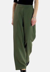 Wijde broek in olijfgroen stof, met een hoge taille en een gladde textuur, gecombineerd met een zwart topje en zwarte schoenen.