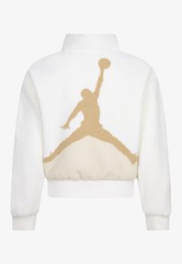 Veste en polaire blanche avec une silhouette beige d'un joueur de basket au dos, dotée d'un col montant et de poignets et d'un ourlet côtelés.