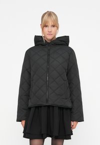 Svart quilted dunjakke med glidelås i front, hette og diagonale diamantmønstre, med sidelommer og en avslappet passform.