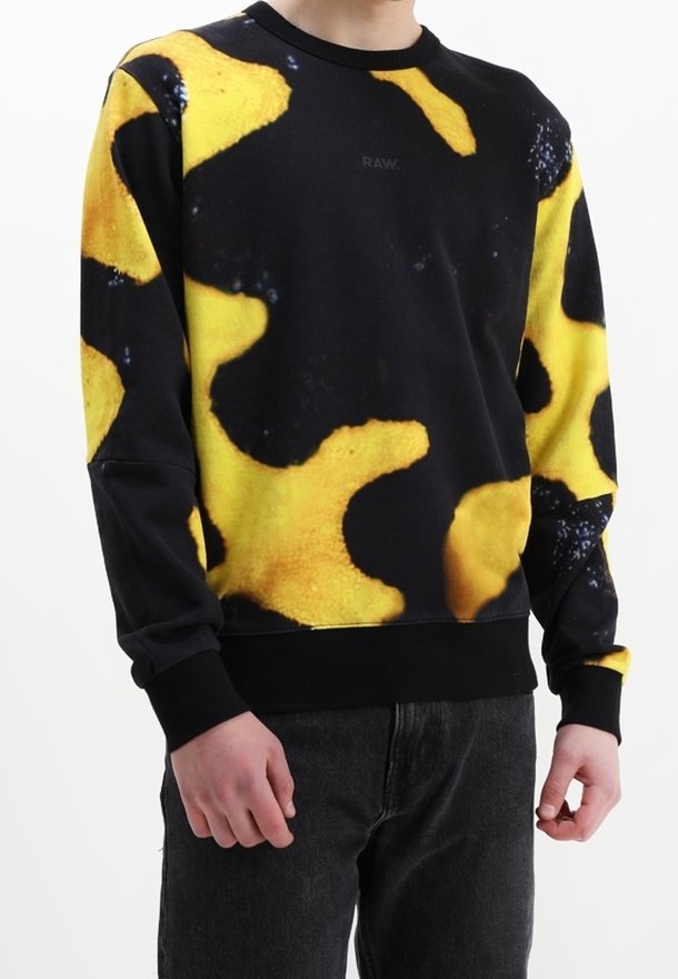 Sudadera negra con patrón abstracto amarillo; escote redondo y mangas largas; tela suave con puños y dobladillo acanalados.