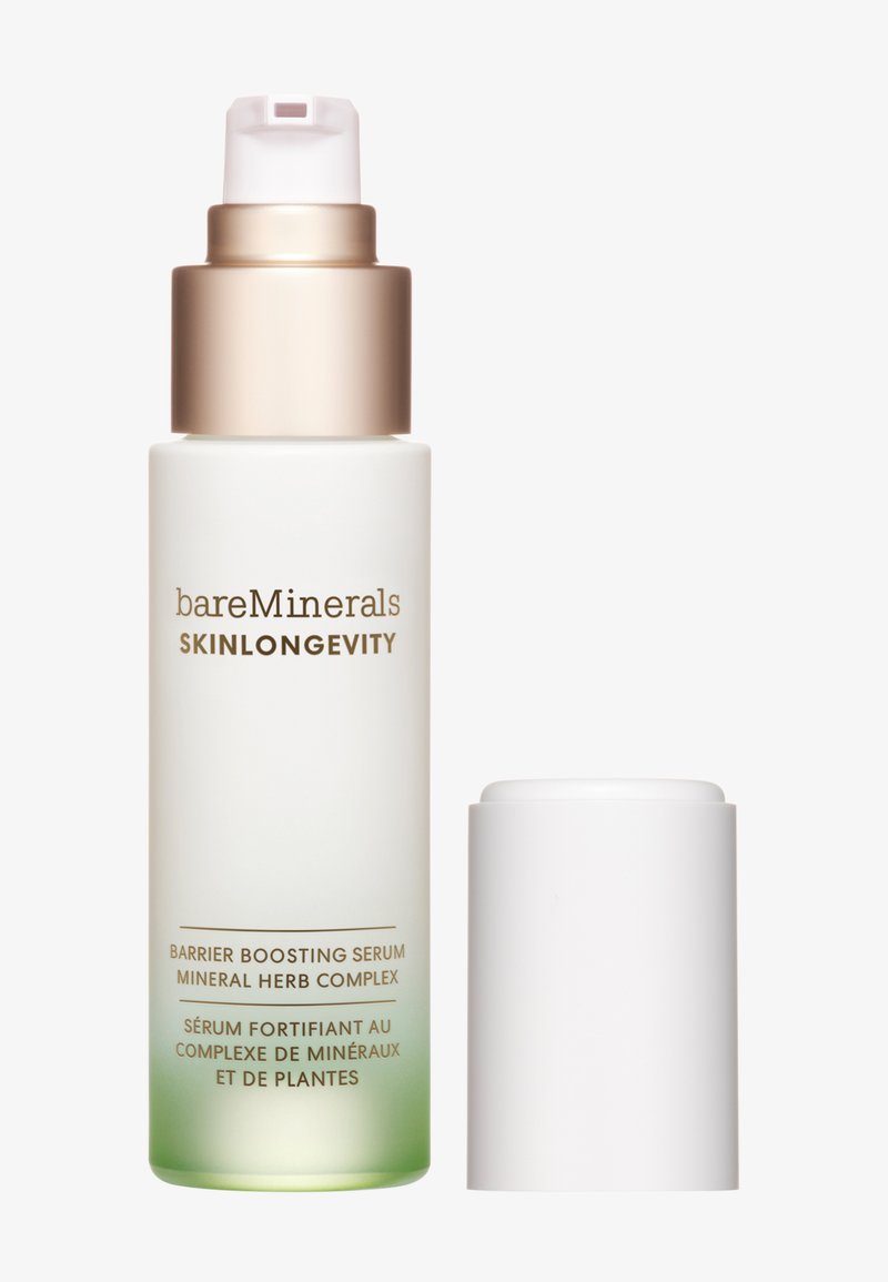 Siero potenziante barriera in una bottiglia trasparente satinata, con una sfumatura dal verde al trasparente. Cappuccio pompante metallico dorato, tappo avvitato bianco. Testo sulla bottiglia.