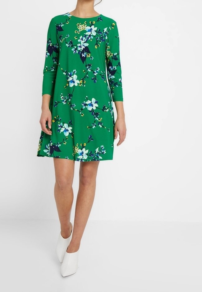 Green dress with a floral pattern featuring blue and yellow flowers. Round neckline, three-quarter sleeves, and a flared hem.