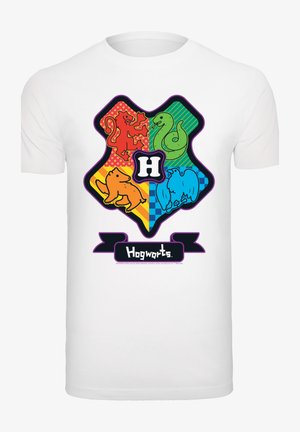 T-shirt bianco con uno stemma di Hogwarts colorato che presenta icone: leone, serpente, orso e aquila. "Hogwarts" è mostrato su un banner nero sottostante.