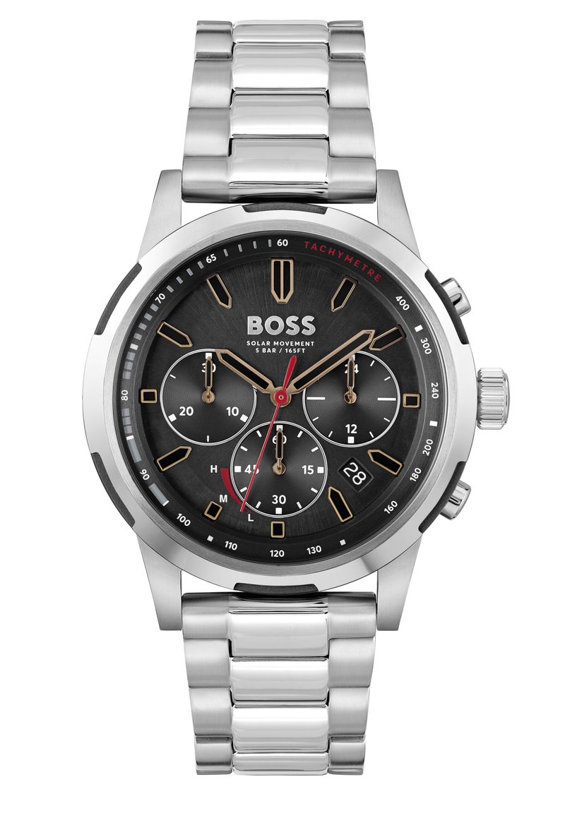 Reloj cronógrafo de acero inoxidable plateado con una esfera negra, acentos dorados, manecillas rojas, tres subesferas y pantalla de fecha. Movimiento solar.