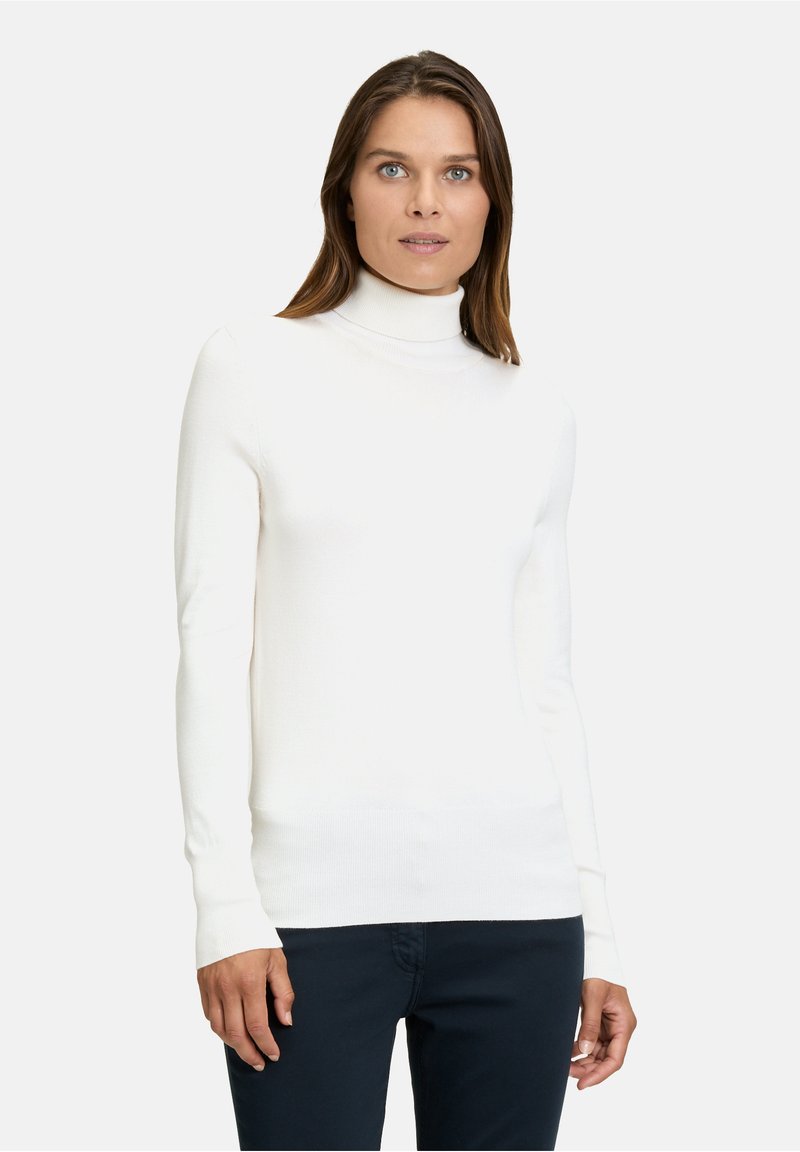 Weißer Rollkragenpullover aus geripptem Stoff, taillierte Passform, lange Ärmel und eine glatte Textur, kombiniert mit dunkler Hose.
