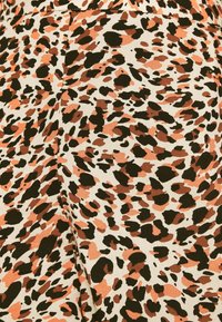 Panterprintstof in tinten van oranje, bruin en zwart op een lichtbeige achtergrond. Makkelijk aan te raken textuur met verschillende vormen en maten van vlekken.